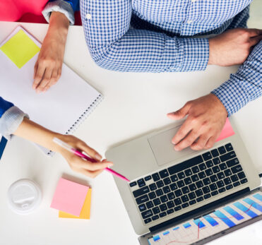 One of analysts making presentation in laptop to her colleague at meeting