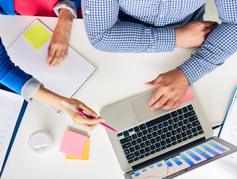 One of analysts making presentation in laptop to her colleague at meeting